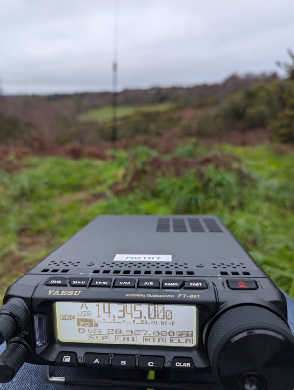 Yaesu FT-891 in the foreground tuned to the 2m band. Out-of-focus background with an antenna somewhere in it.