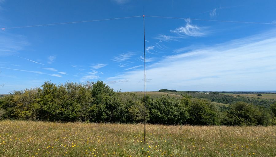 Telescopic field mast supporting an inverted V dipole antenna, scenery in the background