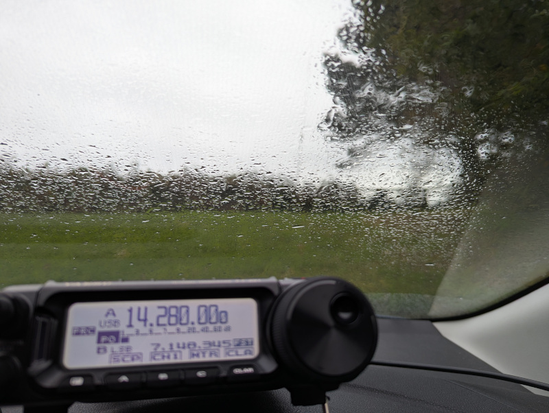 Yaesu FT-891 on a car dashboard, antenna almost visible through a rainy windscreen