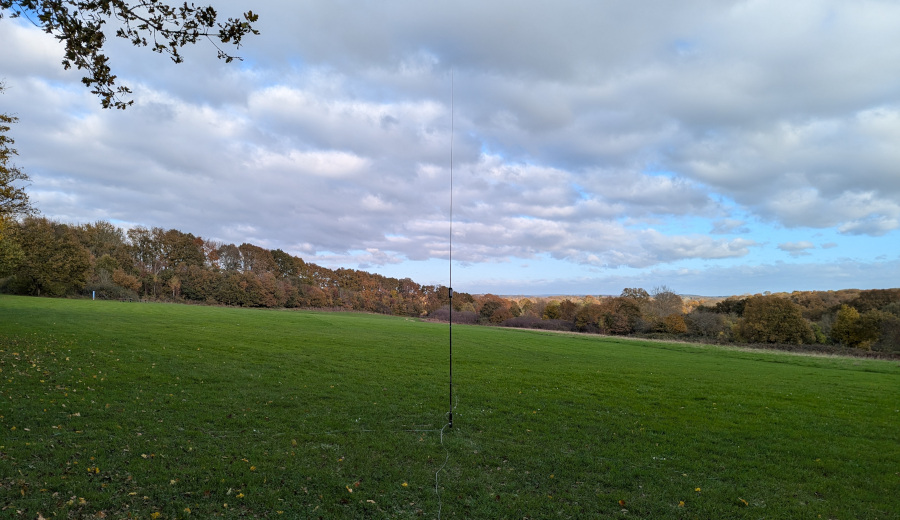 Slanted field with trees in the distance, and an antenna in the middle ground