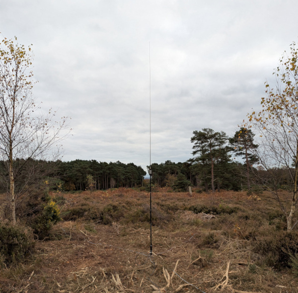 A vertical antenna sat in a firebreak, with heath in the background