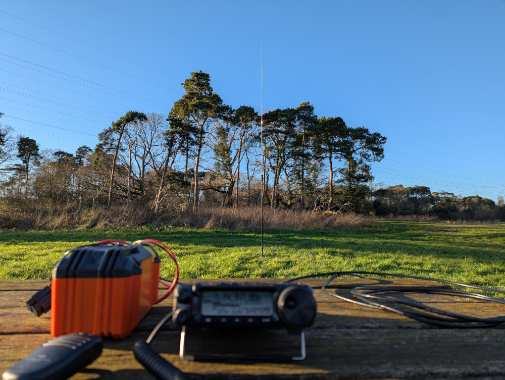 Radio on a picnic table in the foreground, antenna in the background