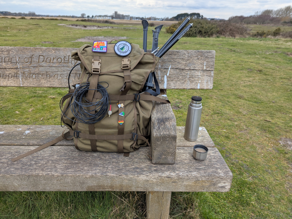 My rucksack, thermos and teacup on a bench, surrounded by greenery