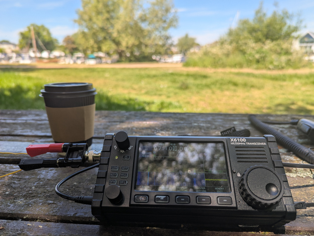 X6100 and coffee cup on a picnic table