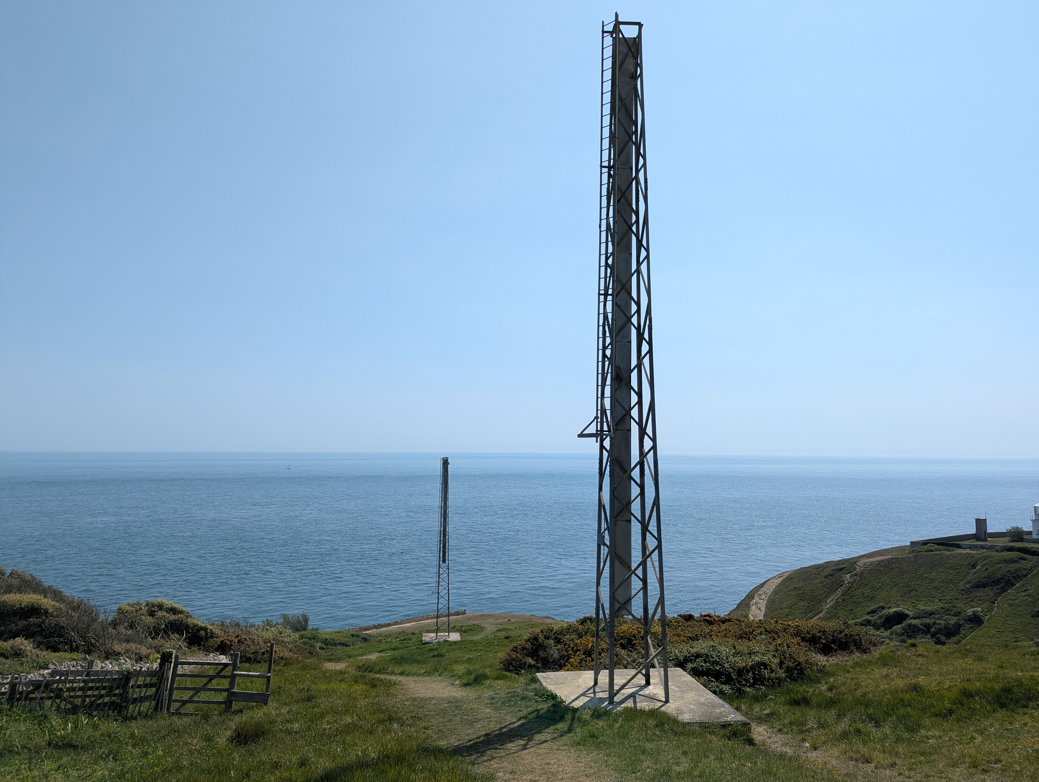Two large metal towers, with the sea in the distance