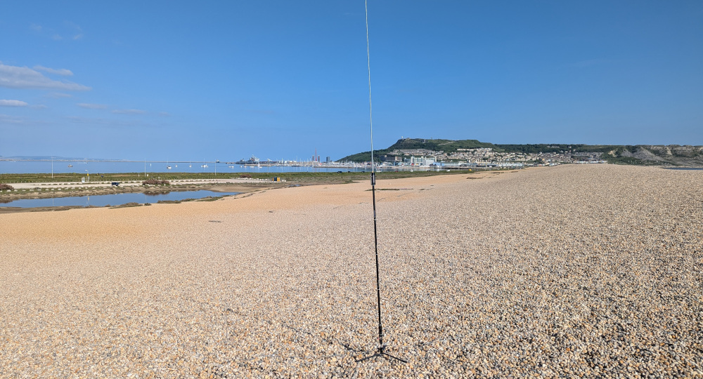 A stony beach with antenna set up, Portland in the background