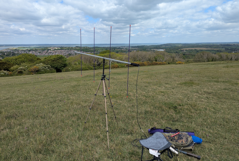 4-element yagi antenna for 2m on a tripod, next to a seat and backpack on the grass