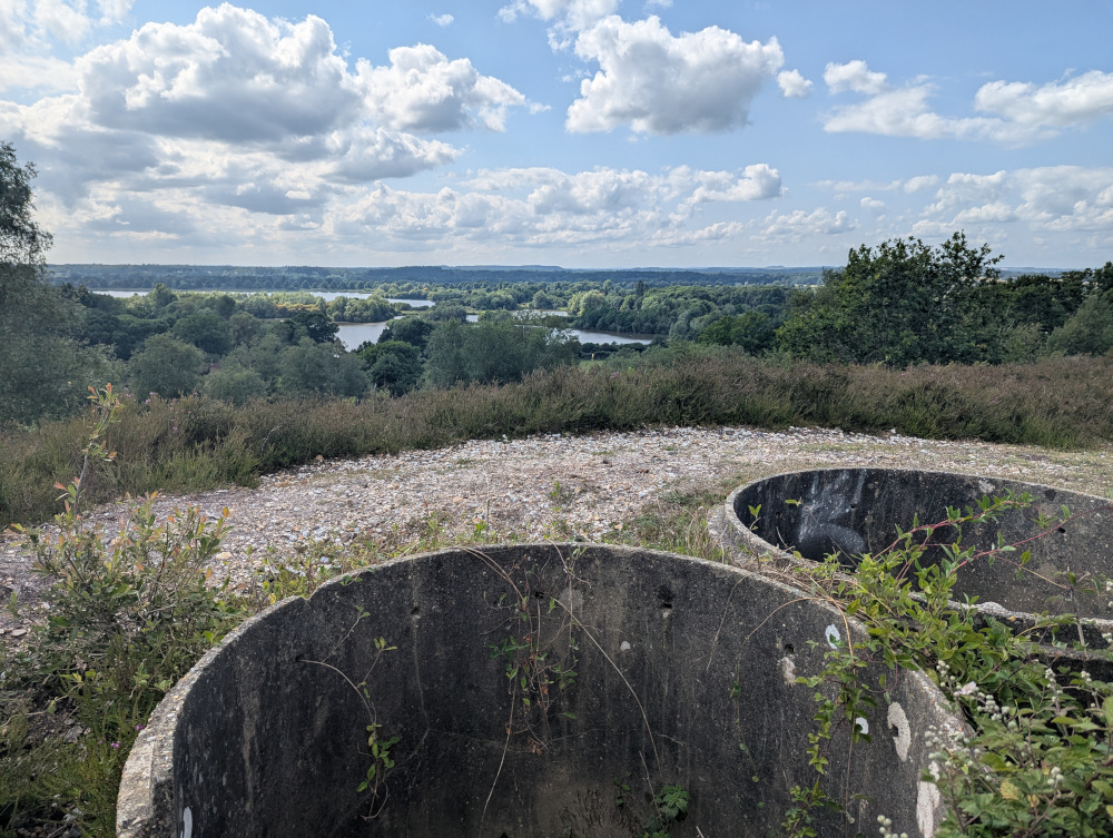Two mostly-buried concrete sewer pipe sections in the foreground, view over the lakes in the background