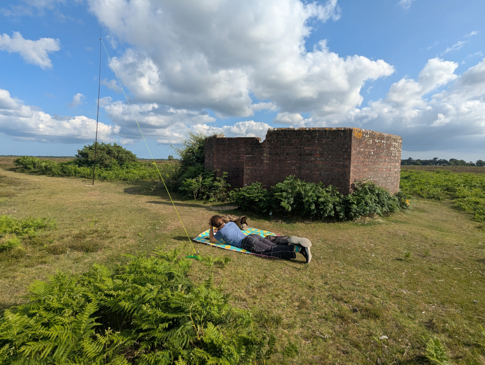 Antenna set up next to the Huff Duff. A picnic blanket is set up with a figure lying on it.