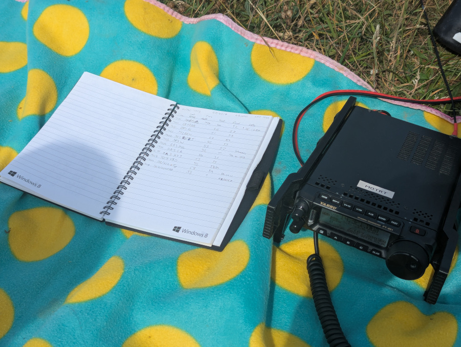 Logbook and FT-891 radio on a green and yellow polkadot picnic blanket