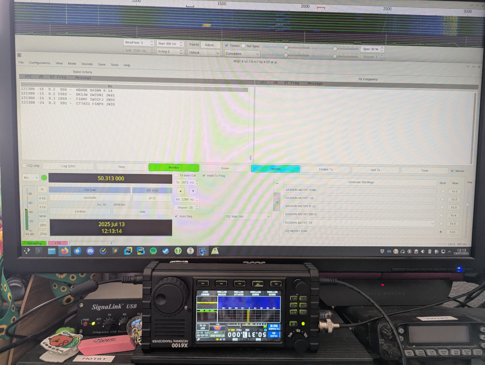 Monitor showing WSJT-X running, with a Xiegu X6100 upside-down below it