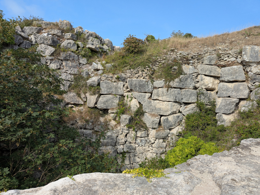 A wall around 8-10 metres high, made of large chunks of stone with gaps between