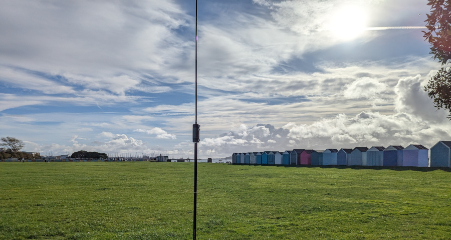 Antenna and beach huts under a wispily clouded sky