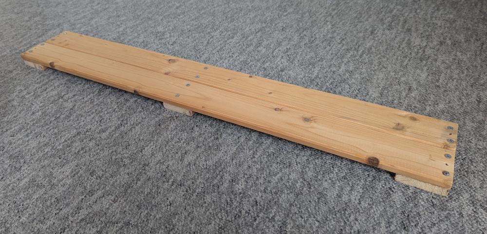 Board made up of two wooden slats screwed down to three wooden feet