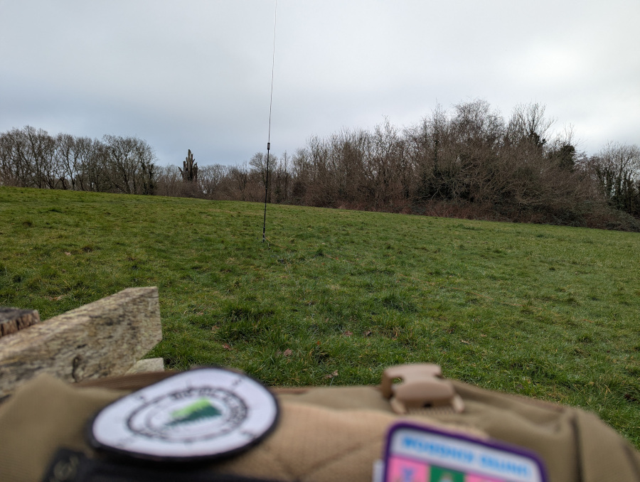 JPC-12 antenna in a green field, with out-of-focus top of my rucksack in the foreground