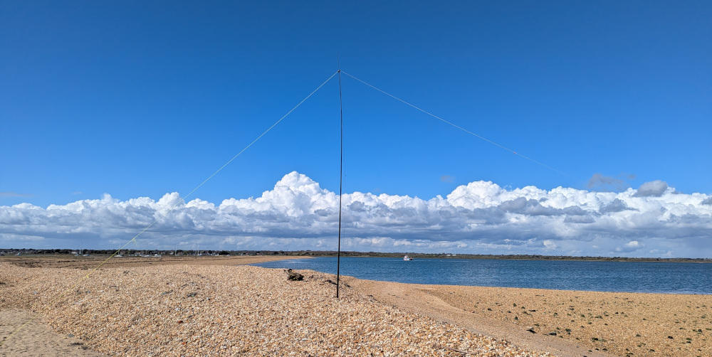 Inverted-V dipole antenna on a shingle beach, sea in the background.