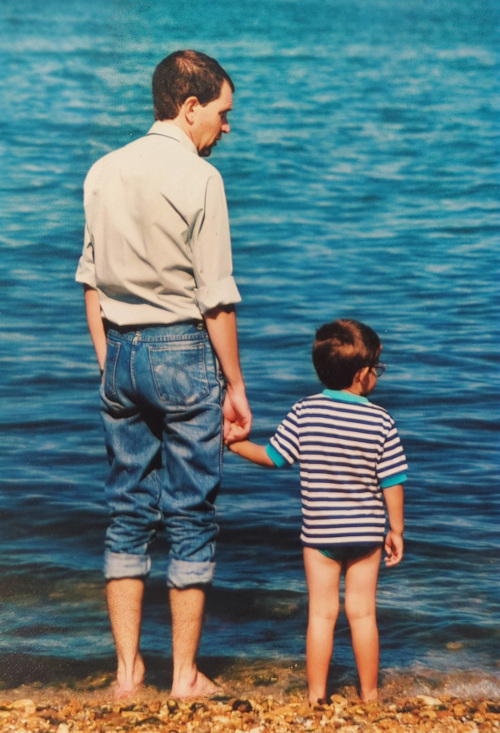 Scan of a photograph from the 80s. I am four years old, holding my dad's hand while paddling in the sea.