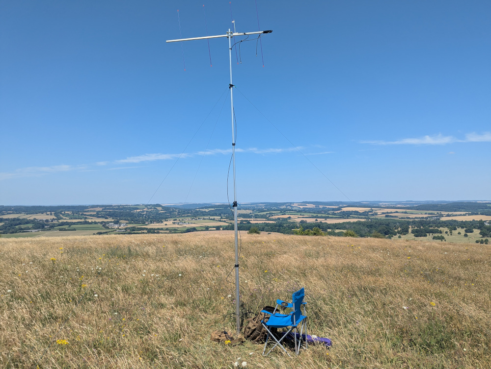 4 element Yagi antenna on a 5 metre pole, surrounded by dry grass. Hills in the background and a blue sky.