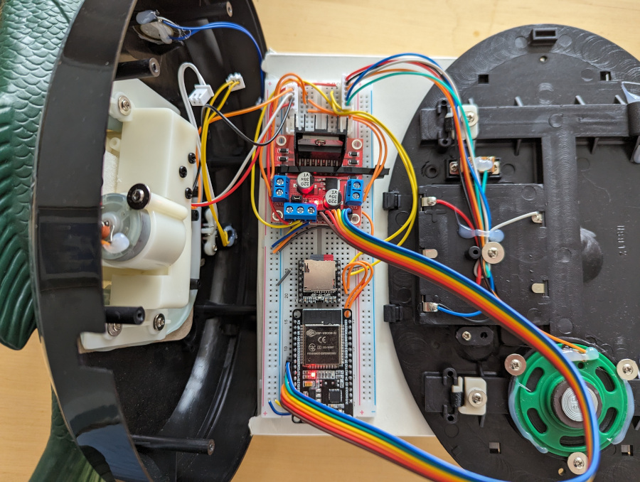 A breadboard and a mess of wiring connected to two halves of a Billy Bass