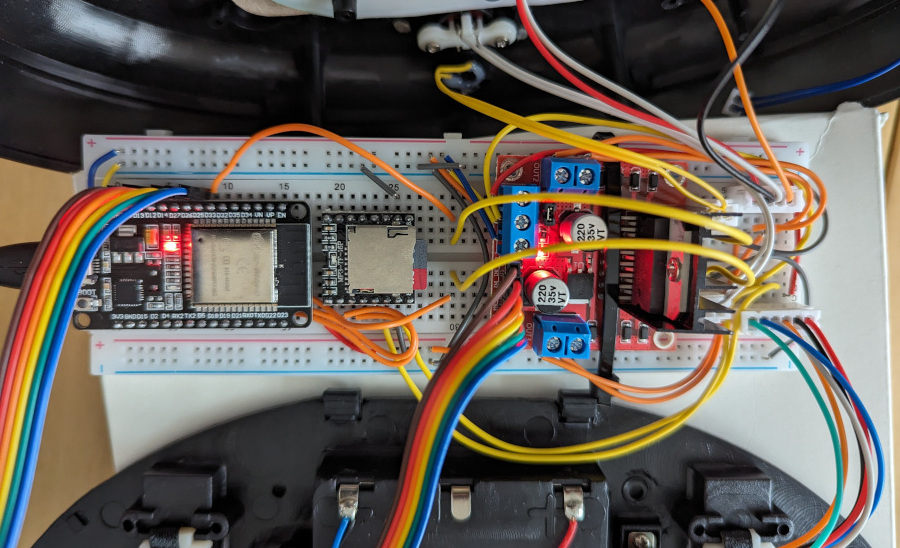 A breadboard and a mess of wiring connected to two halves of a Billy Bass